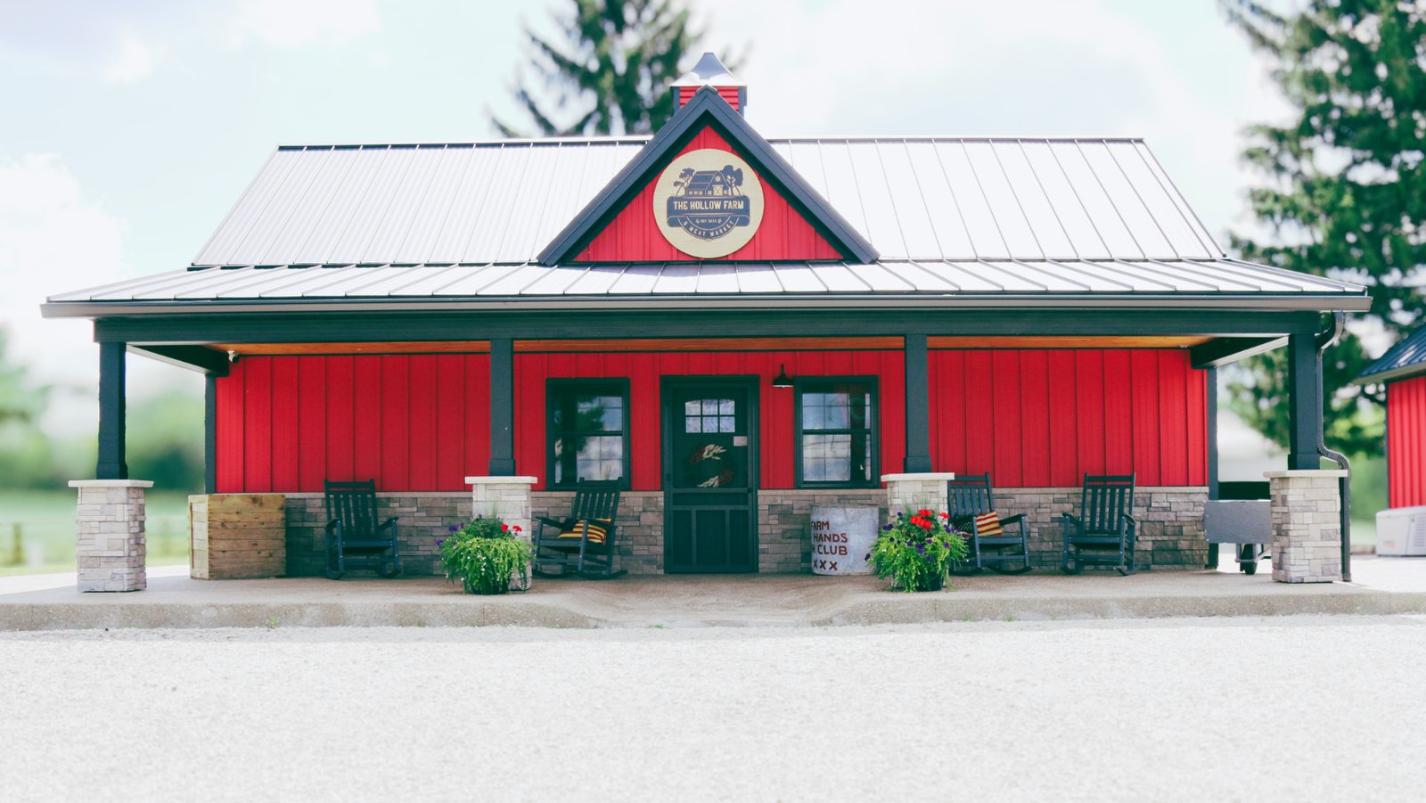The Hollow Farm & Meat Market storefront — red board-and-batten store with a covered porch and rocking chairs